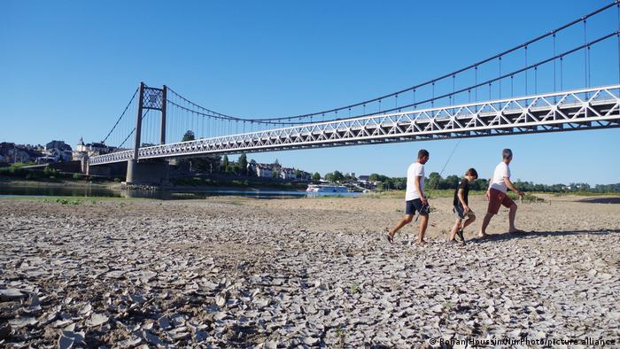 Tres personas caminan sobre el lecho del río Loira.