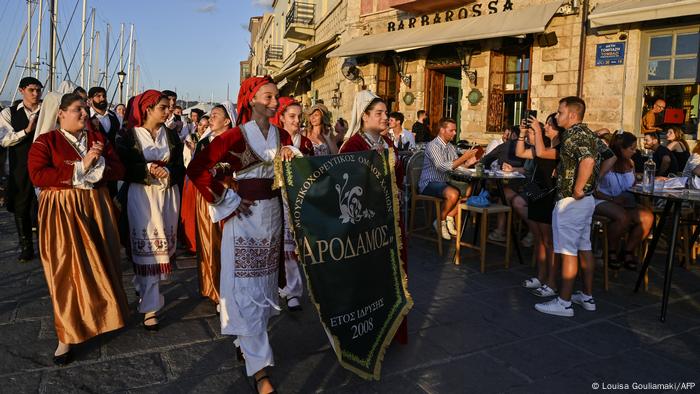 Les touristes regardent un groupe folklorique local marcher dans la vieille ville de La Canée sur l'île grecque de Crète 