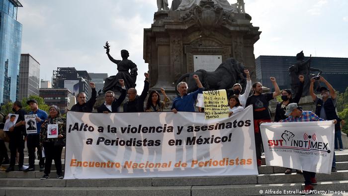 一群记者及家属在墨西哥独立纪念柱前，抗议记者遇害事件