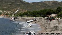People stand on the beach of Sagone in Coggia where boats has been thrown on the French Mediterranean island of Corsica on August 18, 2022. - The violent storms that have been hitting the French Mediterranean since August 16, 2022 left three people dead and several injured on August 28, 2022 in Corsica, where rescue operations are also being carried out at sea. (Photo by PASCAL POCHARD-CASABIANCA / AFP)