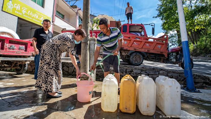 Un trabajador se sitúa encima de un camión que distribuye agua a los residentes con una pancarta en la que se lee Camión de agua para aliviar la sequía de Luoping en la aldea de Luoping del condado de Wushan, en el suroeste de China, en Chongqing.