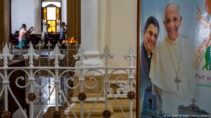 View of a church room, in the foreground a photo of Alvarez with Pope Francis