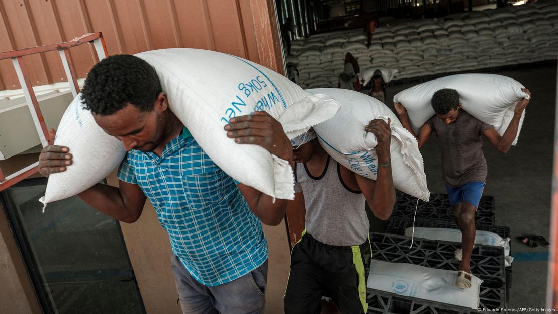 Men carry white sacks of grain in Ethiopia's Abala town