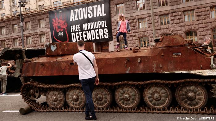 A rusty armored personnel carrier with a banner that reads 'Azovstal, Free Mariupol Defenders'