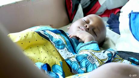 Child sleeping under a colorful quilt.