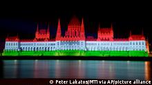 The colors of the Hungarian flag illuminate the Parliament building to mark the national holiday celebrating Hungary's statehood in Budapest, Hungary, Saturday, Aug. 20, 2022. State founder St. Stephen I, the first king of Hungary was crowned in 1000 A.D. (Peter Lakatos/MTI via AP) 