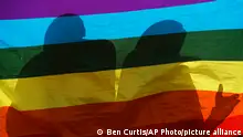 FILE - In this Friday, May 17, 2019 file photo, LGBT refugees living in Kenya stand behind a rainbow flag as they protest against their treatment by authorities, outside an office of the UN refugee agency UNHCR in Nairobi, Kenya. LGBT refugees allege they have been harassed by police in recent weeks in Kenya, which is a rare regional haven for the gay community yet maintains that gay sex is illegal. (AP Photo/Ben Curtis, File)