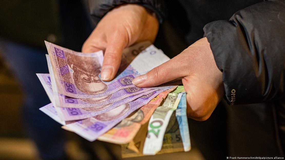 Жена държи в ръцете си украински банкноти - гривни