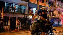 Residents look at Colombian soldiers guarding a street during a curfew imposed in red-zone neighbourhoods due to high numbers of COVID-19 cases in Cali on July 17, 2020. (Photo by Luis ROBAYO / AFP)