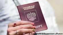 Eine Frauenhand hält einen russischen Pass