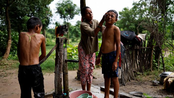 Parwati Sunar and her sons wash in the morning in front of the house at the water pump.