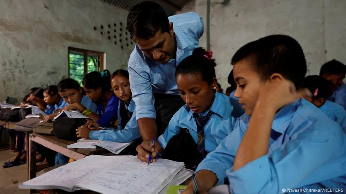 Parwati Sunar is sitting in the classroom, the teacher is pointing out something in her notebook.