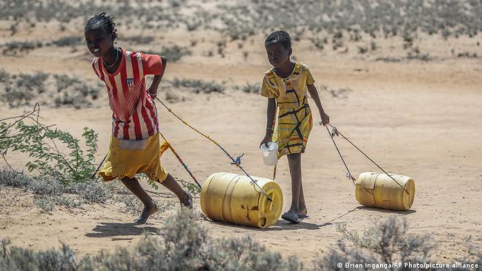 Young girls pull containers of water as they return from a well in northern Kenya. Photo: Brian Inganga / AP Photo / picture alliance
