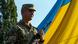 Військовослужбовець поруч з прапором України Військовослужбовець поруч з прапором України