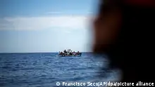 Migranten aus Tunesien warten in einem Holzboot, während sie von Mitgliedern der spanischen Nichtregierungsorganisation Open Arms bei einer Rettungsaktion südlich der italienischen Insel Lampedusa im Mittelmeer unterstützt werden. Bei dieser Rettungsaktion wurden neunzehn Menschen, darunter drei Minderjährige, von den italienischen Zollbehörden gerettet. (AP Photo/Francisco Seco) +++ dpa-Bildfunk +++