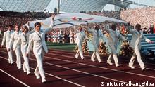 Das Archivbild vom 26.08.1972 zeigt die Mannschaft des bundesrepublikanischen Gold-Achters (Rudern) von Mexiko 1968, die die Olympische Fahne bei der Eröffnungsfeier in das Münchner Olympiastadion trägt.
