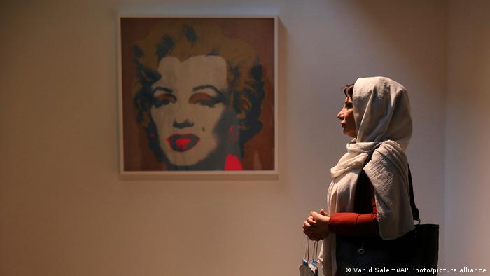 Woman looks at warhol painting of Marilyn Monroe