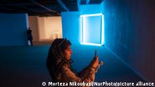 An Iranian young woman uses her smartphone while standing next to a conceptual artwork by the American artist, Dan Flavin, while visiting of the Minimalism and Conceptual Art exhibition at Tehran's Museum of Contemporary Art July 14, 2022. (Photo by Morteza Nikoubazl/NurPhoto)