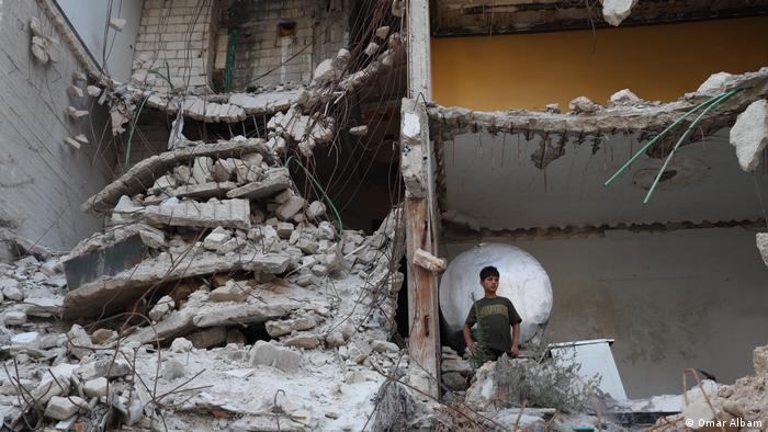 A child standing inside his half-destroyed house in Idlib 