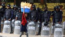 A woman walks past police officers as Angola's election commission says ruling MPLA party leads with 52% majority, after the general election close in Luanda, Angola August 25, 2022. REUTERS/Siphiwe Sibeko TPX IMAGES OF THE DAY 