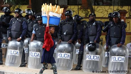 Eine Frau läuft an Polizisten mit Kampfausrüstung vorbei