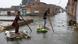 People cross a flooded street on makeshift rafts in Hyderabad, Pakistan. People cross a flooded street on makeshift rafts in Hyderabad, Pakistan.