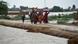 Women and children walk with their belongings towards a higher ground following rains and floods during the monsoon season in Dera Allah Yar, district Jafferabad, Balochistan,