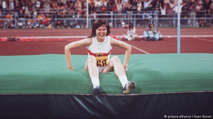 Hochspringerin Ulrike Meyfarth sitzt nach einem erfolgreichen Sprung lachend auf der Matte
