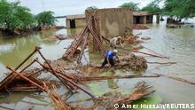 People retrieve bamboos from a damaged house following rains and floods during the monsoon season in Dera Allah Yar, district Jafferabad, Balochistan, Pakistan August 25, 2022. REUTERS/Amer Hussain NO RESALES. NO ARCHIVES.