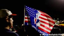 A supporter of former U.S. President Donald Trump waves a flag as he and others gather outside his Mar-a-Lago home after Trump said that FBI agents raided it, in Palm Beach, Florida, U.S., August 8, 2022. REUTERS/Marco Bello