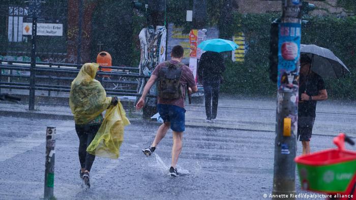 Passanten in einem heftigen Regensturm in Berlin