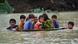 Foto de un hombre que ayuda a varios niños y niñas a cruzar un área inundada en Pakistán. Foto de un hombre que ayuda a varios niños y niñas a cruzar un área inundada en Pakistán.