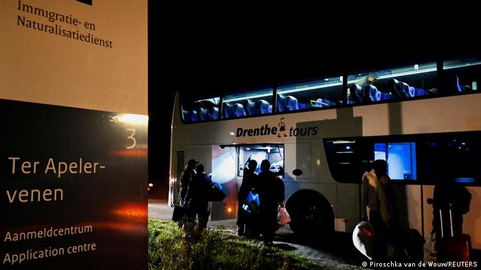 Refugees are seen entering a bus outside the Ter Apel asylum reception center in the Netherlands