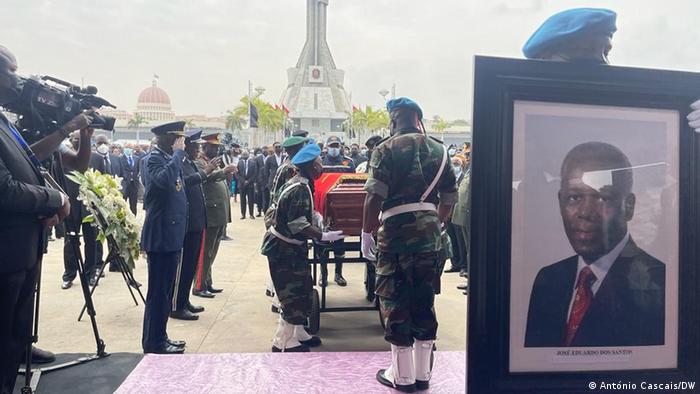 a portrait of dos Santos carried ahead of the coffin, supported by military-clad pallbearers