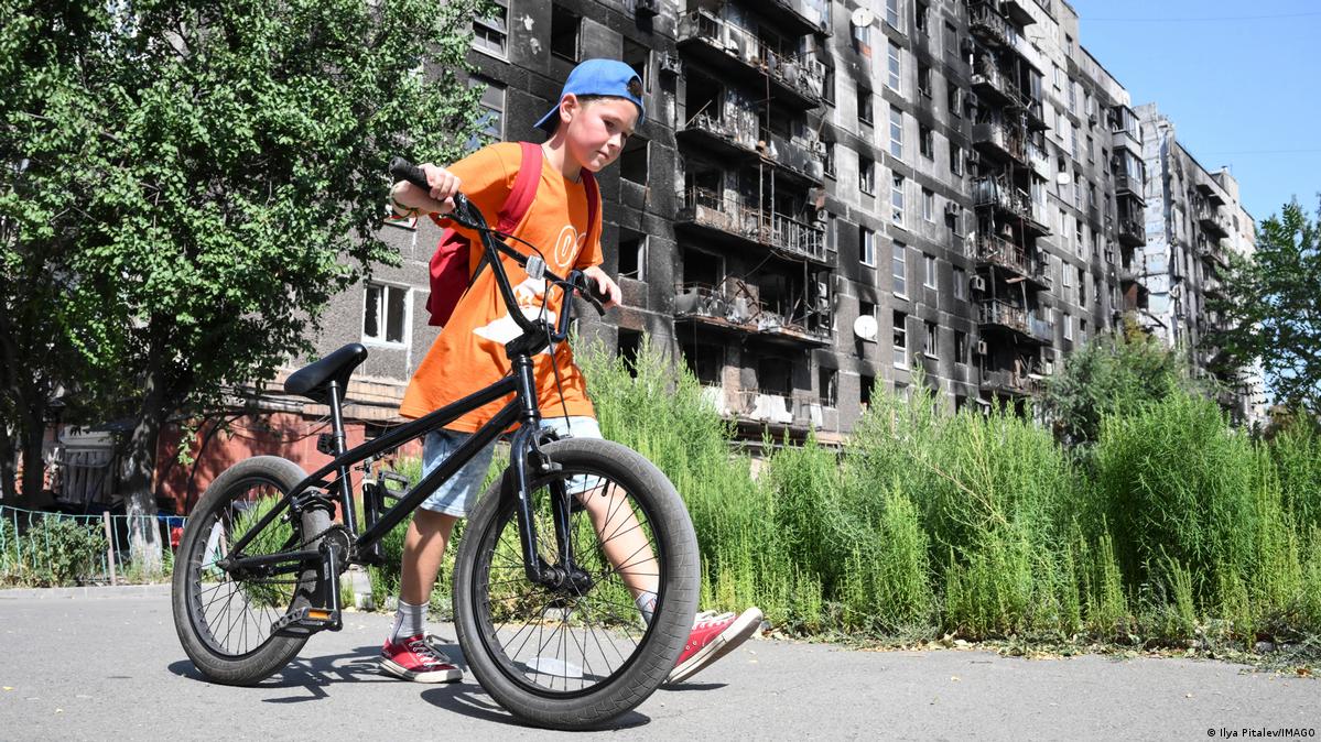 Boy with a bicycle outside a damaged apartment bloc in Ukraine