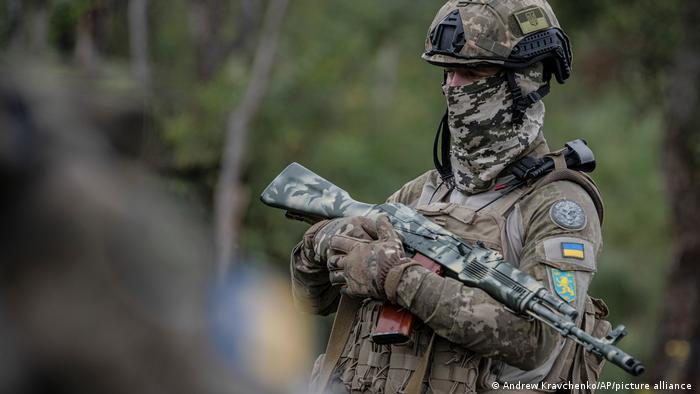 A volunteer soldier in battlegear wearing a camouflage scarf around his face attends training outside Kyiv.