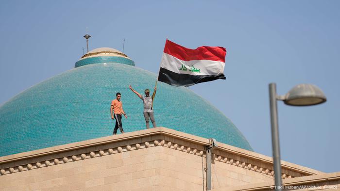 Supporters of Shiite cleric Muqtada al-Sadr wave a national flag from the roof of the Government Palace during a demonstration in Baghdad.