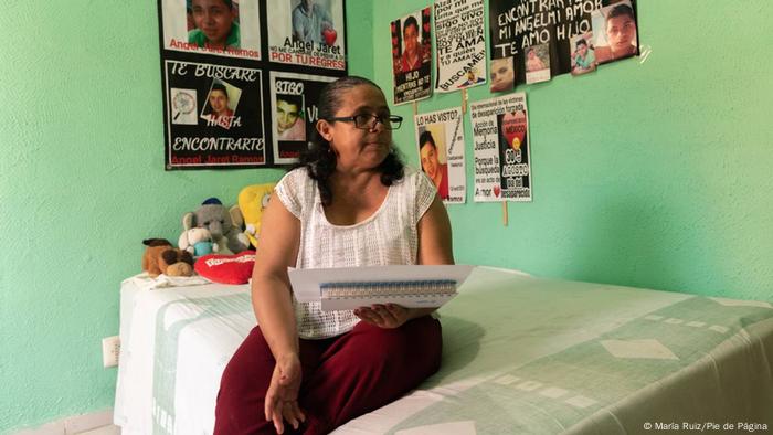 A woman sits on her son's bed holding a poem she has written.
