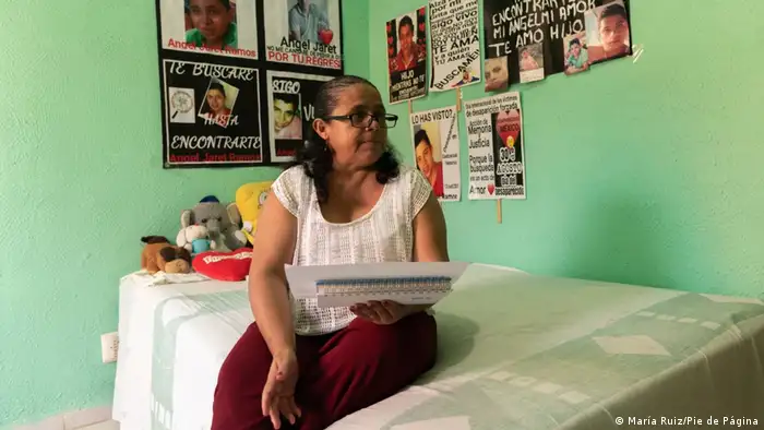 A woman sits on her son's bed holding a poem she has written.