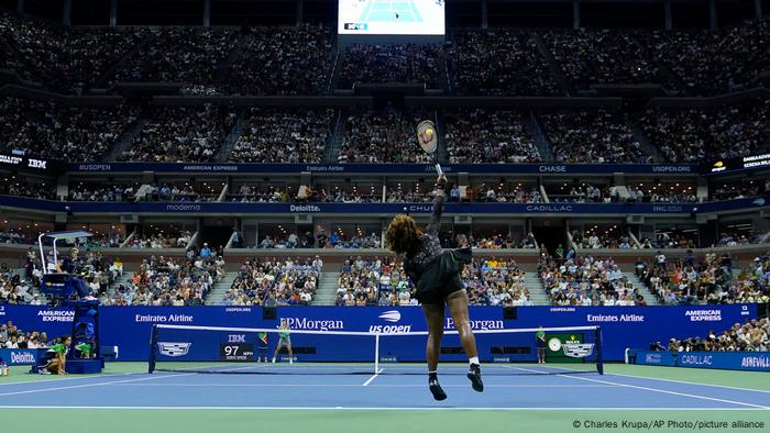 Serena Williams schlägt aus der Hinteransicht auf und trifft den Ball über dem Kopf