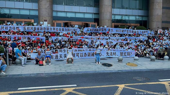 People hold banners and chant slogans during a protest at the entrance to a branch of China's central bank in Zhengzhou People hold banners and chant slogans during a protest at the entrance to a branch of China's central bank in Zhengzhou