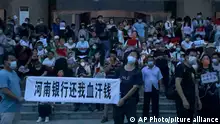 People hold banners and chant slogans stage a protest at the entrance to a branch of China's central bank in Zhengzhou in central China's Henan Province on July 10, 2022. A large crowd of angry Chinese bank depositors faced off with police Sunday, some reportedly injured as they were roughly taken away, in a case that has drawn attention because of earlier attempts to use a COVID-19 tracking app to prevent them from mobilising. (AP Photo)