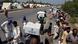 Displaced families and tents on a roadside in Pakistan; some are carrying boxes marked "flood emergeny response 2022." Photo from August 29, 2022. Displaced families and tents on a roadside in Pakistan; some are carrying boxes marked "flood emergeny response 2022." Photo from August 29, 2022.