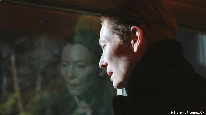 Film still 'The Eternal Daughter': Tilda Swinton looks through a window, which reflects her face.