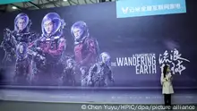 Visitors pose in front of a poster of Chinese sci-fi blockbuster The Wandering Earth during an expo in Shanghai, China, 15 March 2019. Over four years of devotion, 7,000 crew members and several investors willing to take the plunge ¡ª it took a lot for Chinese sci-fi blockbuster The Wandering Earth to become a surprise hit. The film, released during February's Lunar New Year holiday earned over 4.63 billion yuan ($689.74 million) as of March 19. That made it China's second-highest grossing film of all time, after 2017 action flick Wolf Warrior 2. The Wandering Earth is an adaptation of a novella by acclaimed Chinese sci-fi author Liu Cixin, winner of the prestigious Hugo Award for sci-fi fiction writing. Set in a distant future in which the sun is about to expand into red giant and devour the Earth, engineers from around the world scramble to devise a plan to move the planet into a new solar system using giant thrusters. Things take a turn for the worse when the Earth nears Jupiter, sparking a desperate mission to save humanity from extinction.