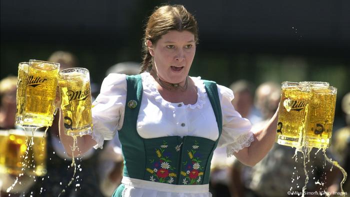 Woman in a dirndl carries beer mugs