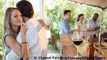 Couple embracing while using mobile phone in restaurant || Modellfreigabe vorhanden