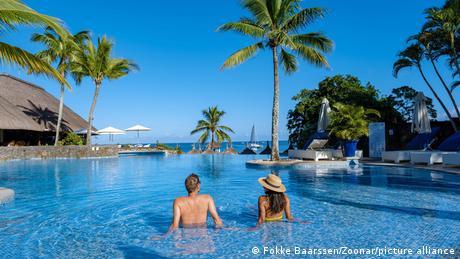 Beautiful tropical beachfront hotel resort with a swimming pool, sun-loungers, and palm trees.