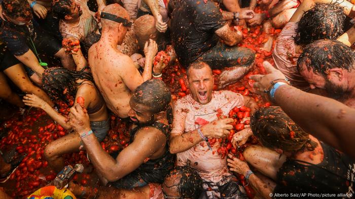 Algunos de los participantes en la llamada Tomatina se revuelven en toneladas de tomates diseminados en una calle de Buñol, un pueblo español cercano a Valencia. Después de dos pandémicos años, las fiestas patronales y los festivales de todo tipo han alegrado el verano de españoles y turistas. ¿Qué sentido tiene revolcarse entre tomates? A menudo, el esparcimiento no va de la mano con la razón.