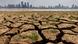 A city in the background with cracks running through the partially dried-up river bed of the Gan River in the foreground A city in the background with cracks running through the partially dried-up river bed of the Gan River in the foreground
